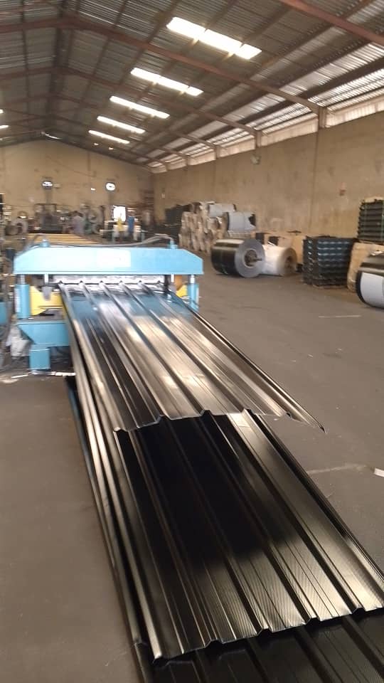 Straight-profile aluminium roofing sheets emerging from forming equipment